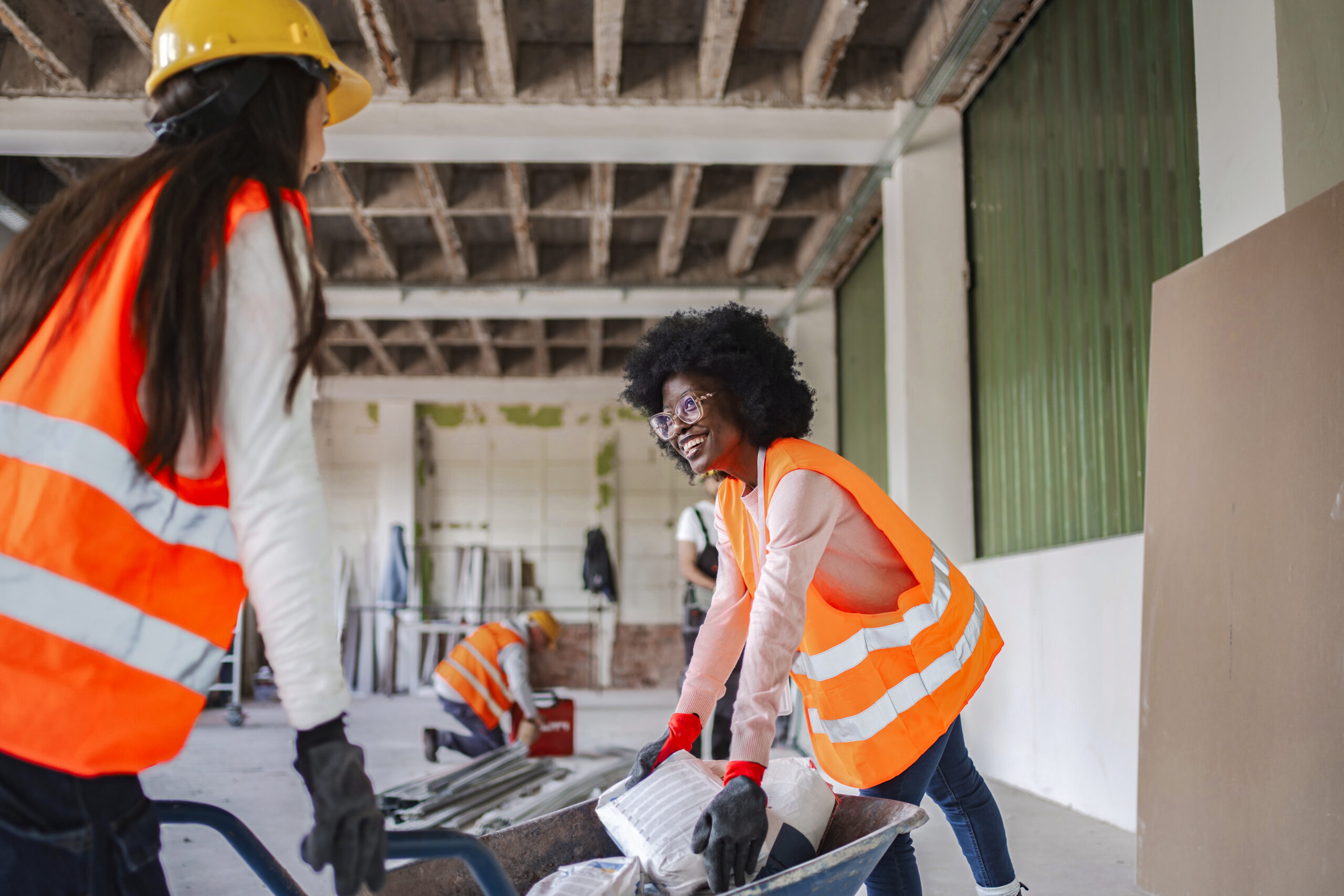 construction workers pushing wheelbarrow at building site